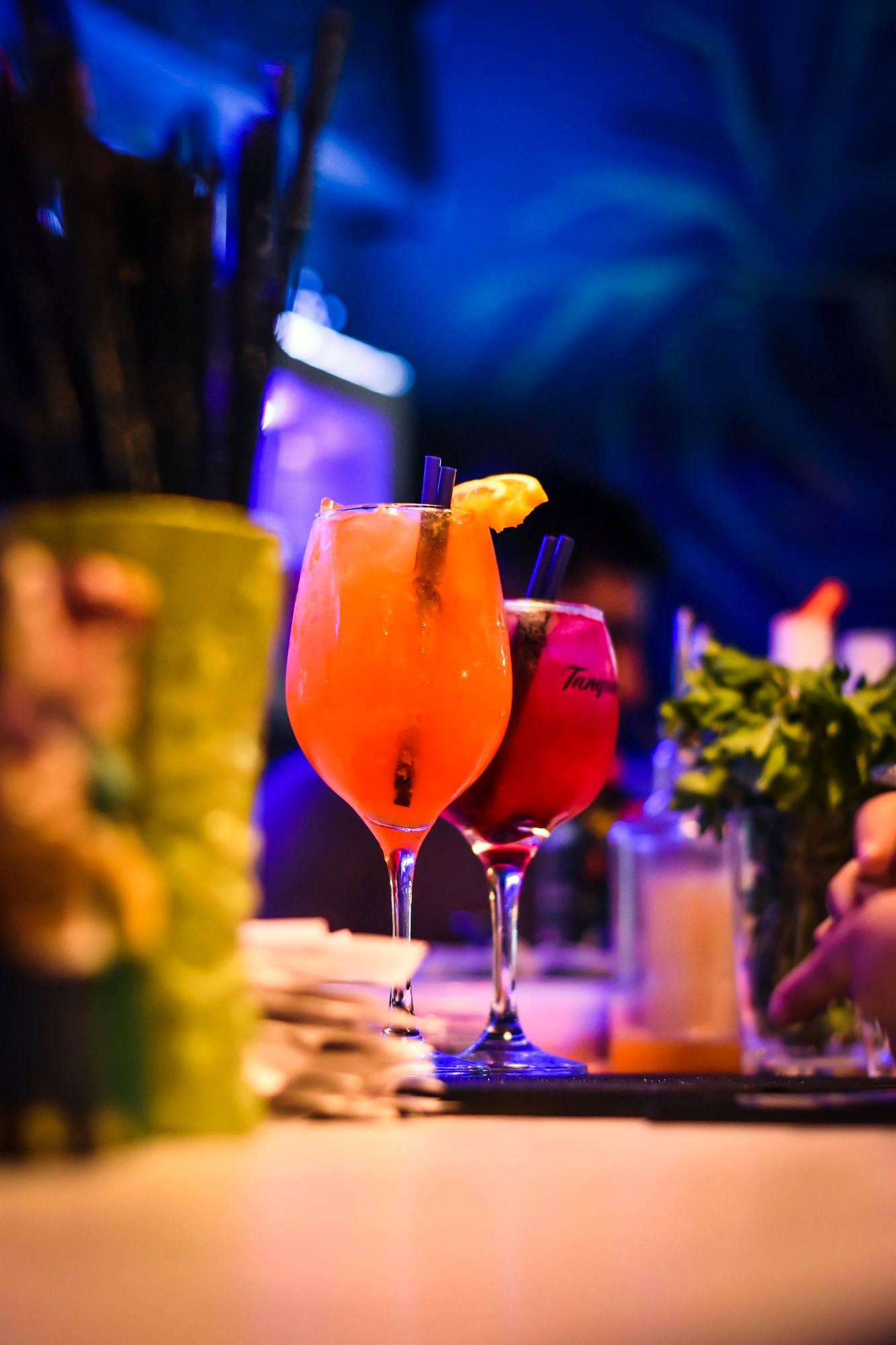 Bar de coctelería de noche, luz baja y ámbar, detalle de barra.