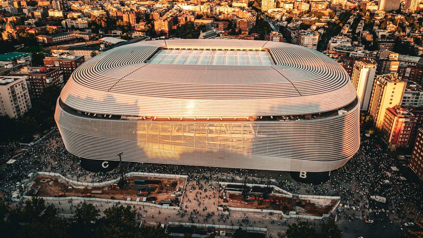 Grada o fachada de estadio en día de partido, luz de final de tarde.